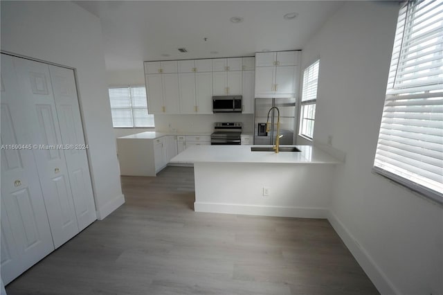 kitchen with light hardwood / wood-style floors, a healthy amount of sunlight, sink, white cabinetry, and appliances with stainless steel finishes