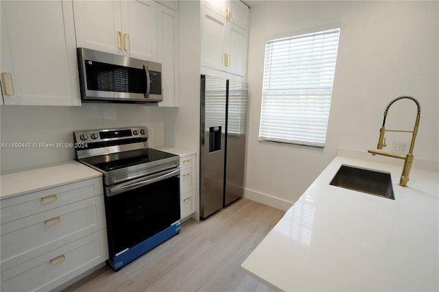 kitchen featuring light hardwood / wood-style flooring, white cabinets, sink, and stainless steel appliances