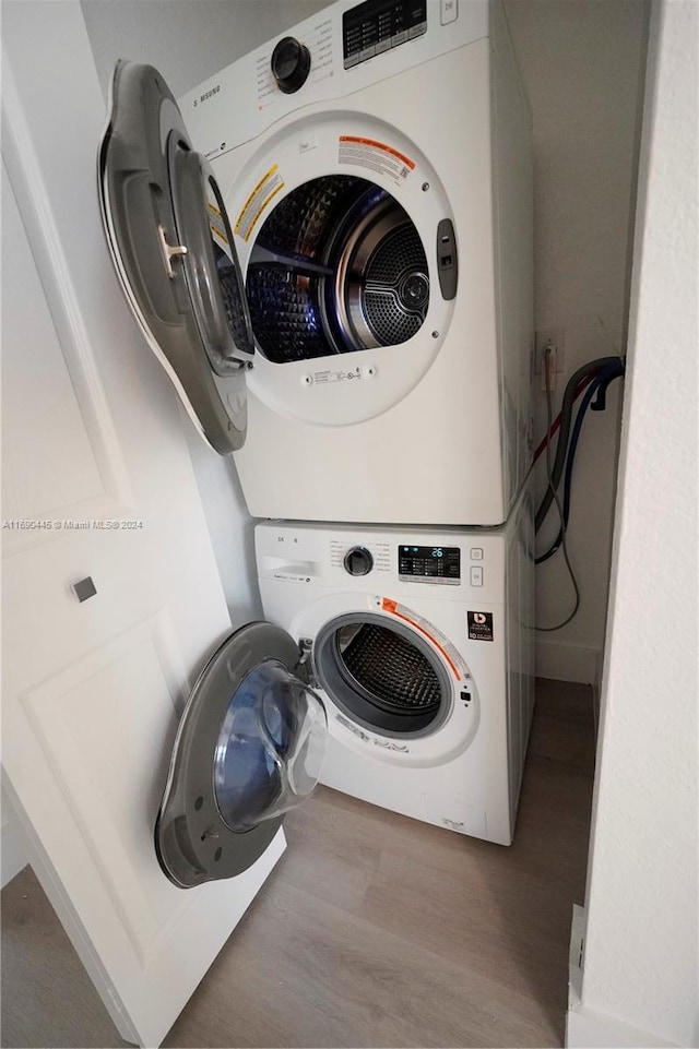 washroom featuring hardwood / wood-style flooring and stacked washer / dryer