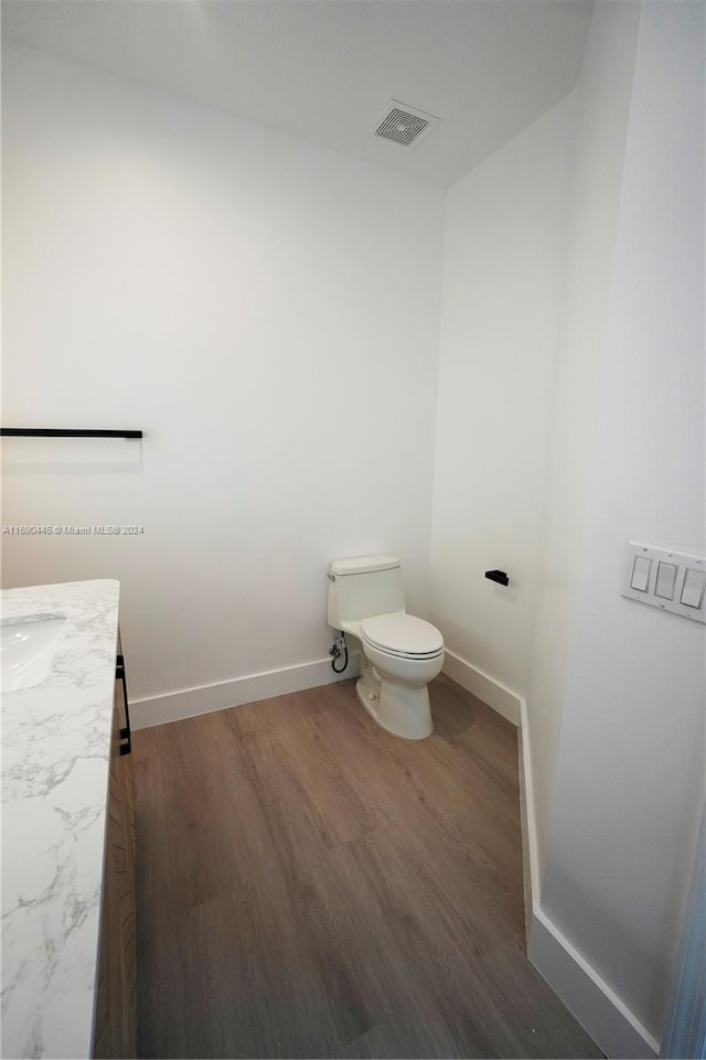 bathroom with toilet, vanity, and hardwood / wood-style floors