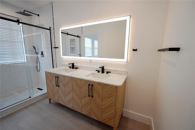 bathroom with hardwood / wood-style floors, vanity, and a shower with shower door