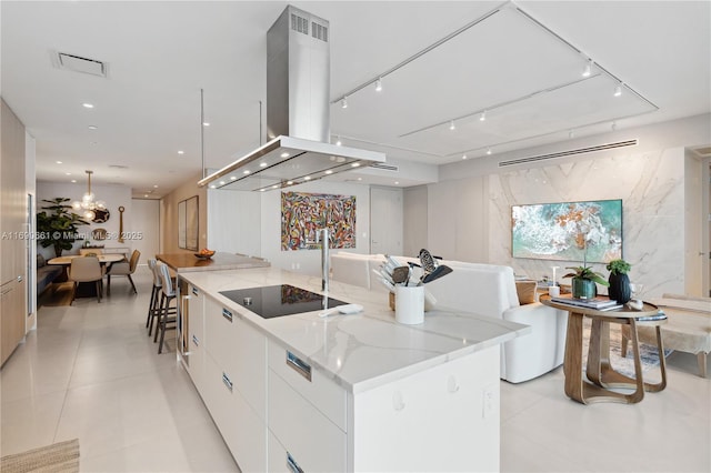 kitchen with a spacious island, white cabinets, black electric stovetop, light tile patterned floors, and island range hood