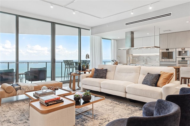 living room with a wall of windows, a water view, and sink