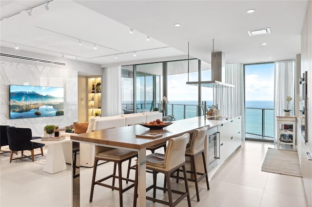 tiled dining space featuring sink, a wall of windows, a water view, and wine cooler