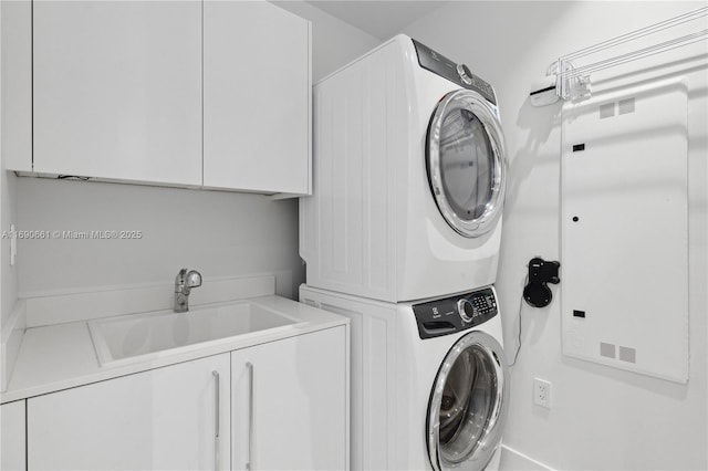 clothes washing area with sink, cabinets, and stacked washing maching and dryer