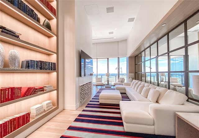 living room with built in shelves, hardwood / wood-style floors, and a towering ceiling