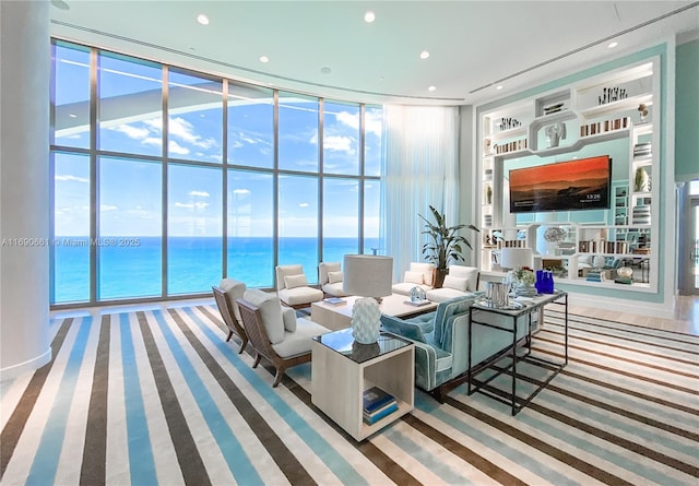 carpeted living room featuring built in shelves, a water view, and floor to ceiling windows