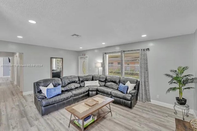 living room featuring light wood-type flooring and a textured ceiling