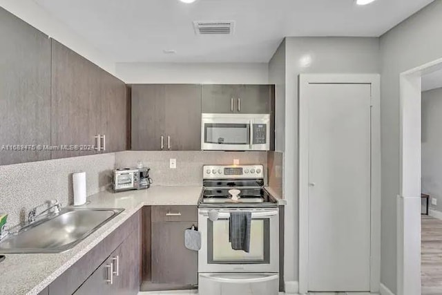 kitchen featuring light hardwood / wood-style floors, sink, backsplash, and appliances with stainless steel finishes