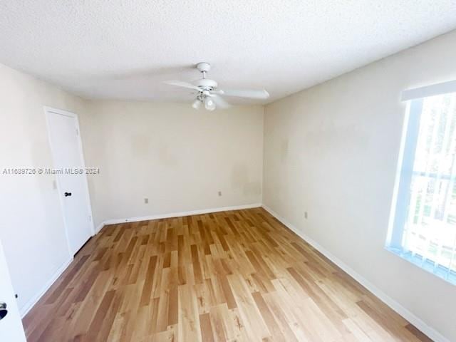 spare room with light hardwood / wood-style floors and a textured ceiling