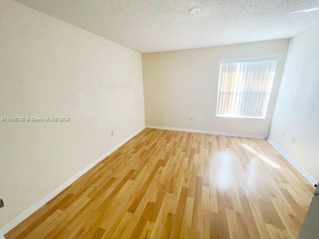 spare room featuring light hardwood / wood-style flooring and a textured ceiling