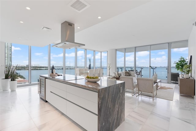 kitchen featuring black electric stovetop, island exhaust hood, wine cooler, floor to ceiling windows, and modern cabinets