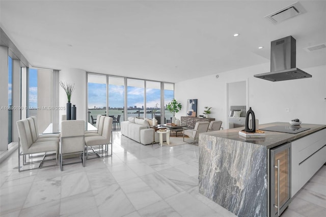 kitchen with visible vents, modern cabinets, expansive windows, ventilation hood, and beverage cooler