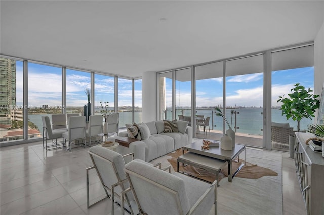 living room with a water view, expansive windows, light tile patterned flooring, and a wealth of natural light