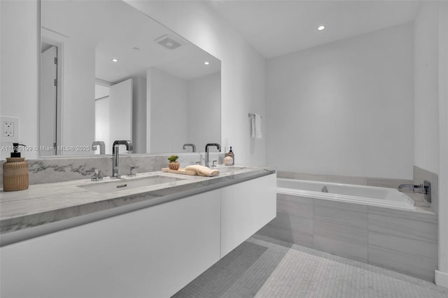 bathroom with tile patterned flooring, vanity, and a relaxing tiled tub