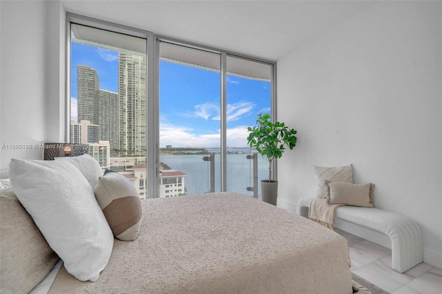 bedroom featuring a water view, baseboards, floor to ceiling windows, and access to exterior