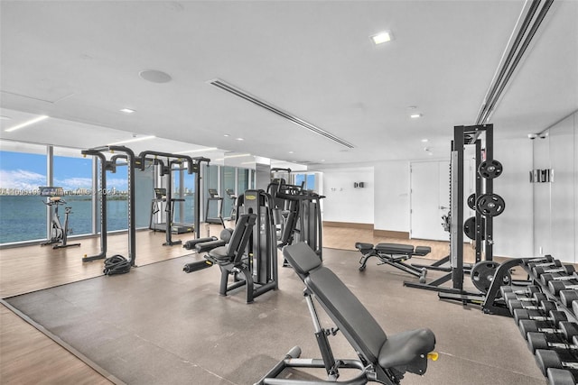 exercise room featuring a water view and a wall of windows