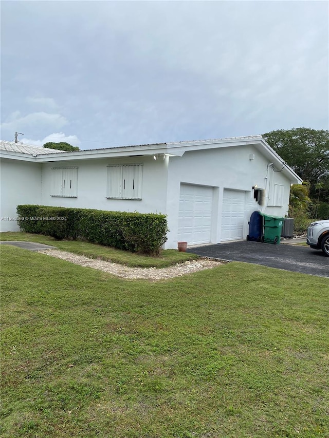 view of side of property with a garage, central AC unit, and a lawn