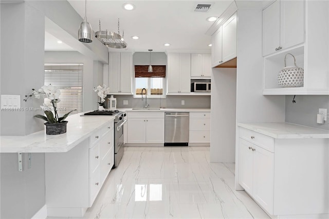 kitchen featuring stainless steel appliances, hanging light fixtures, white cabinetry, and sink