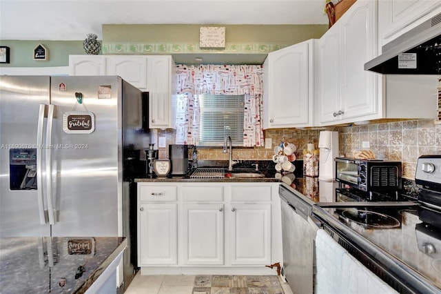 kitchen featuring dark stone counters, sink, exhaust hood, white cabinetry, and appliances with stainless steel finishes