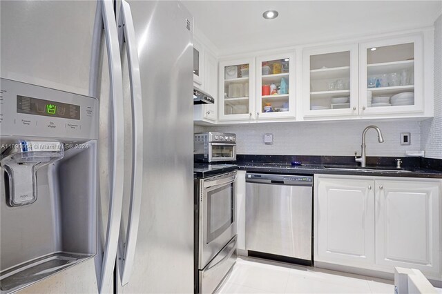 780 NE 69th St Unit 2506, Miami, FL 33138 - kitchen featuring appliances with stainless steel finishes, a sink, white cabinets, tasteful backsplash, and glass insert cabinets