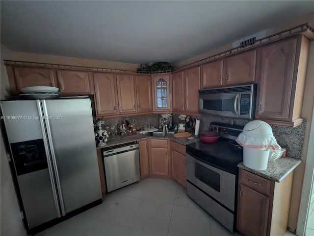 kitchen featuring stainless steel appliances, dark stone countertops, sink, and decorative backsplash