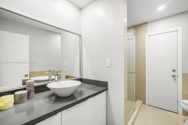 bathroom with tile patterned floors, toilet, a stall shower, and vanity