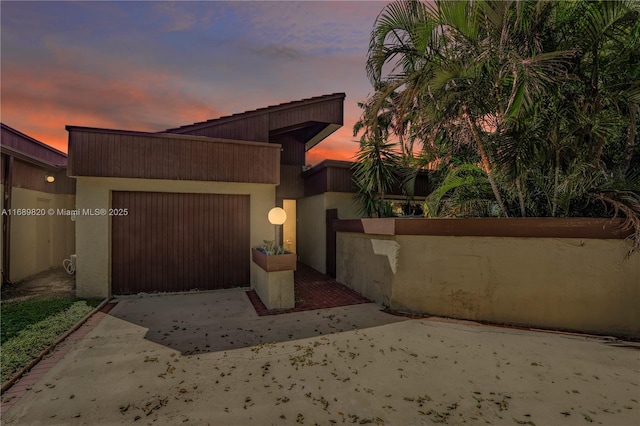 view of front of house featuring stucco siding, driveway, an attached garage, and fence