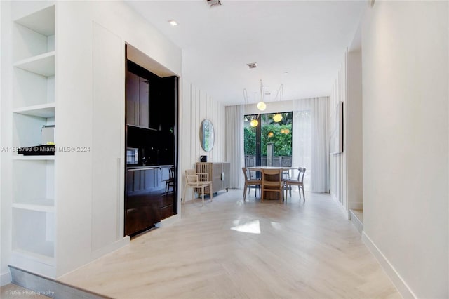 hallway featuring light wood-type flooring and built in shelves