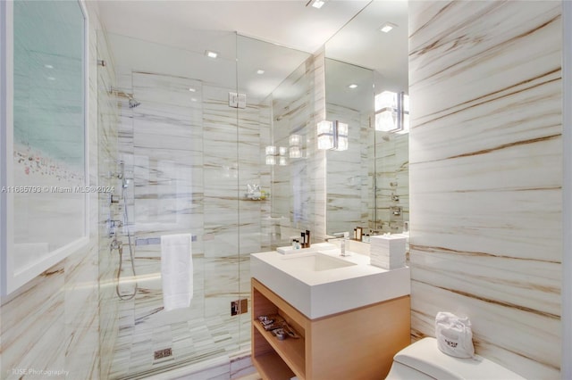 bathroom with walk in shower, vanity, toilet, and tile walls