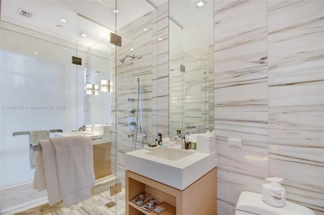 bathroom with vanity, an enclosed shower, and tile walls