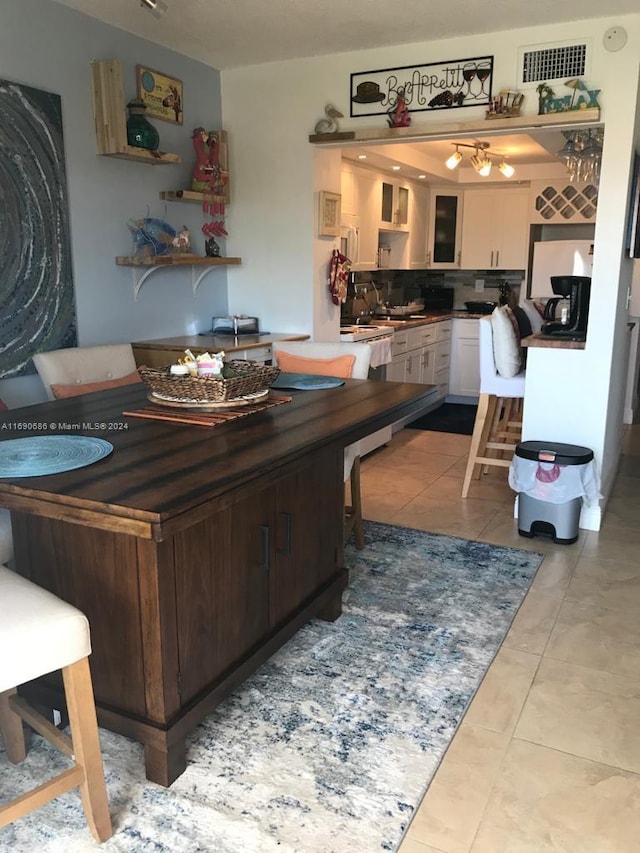 interior space with dark brown cabinetry, light tile patterned flooring, white cabinetry, tasteful backsplash, and dishwasher