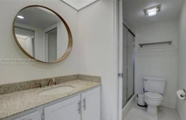 bathroom with toilet, vanity, and a shower with door