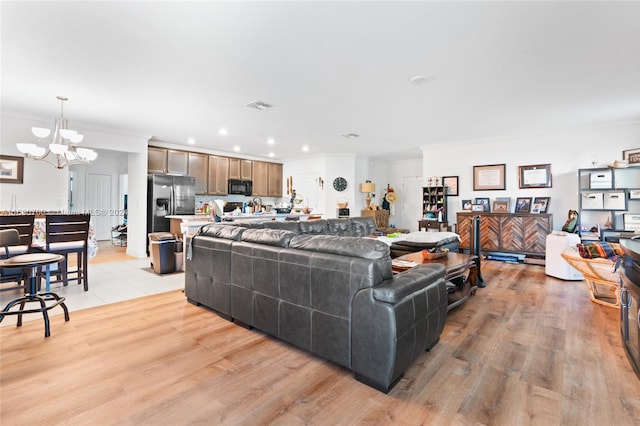 living room with a chandelier, ornamental molding, and light hardwood / wood-style flooring