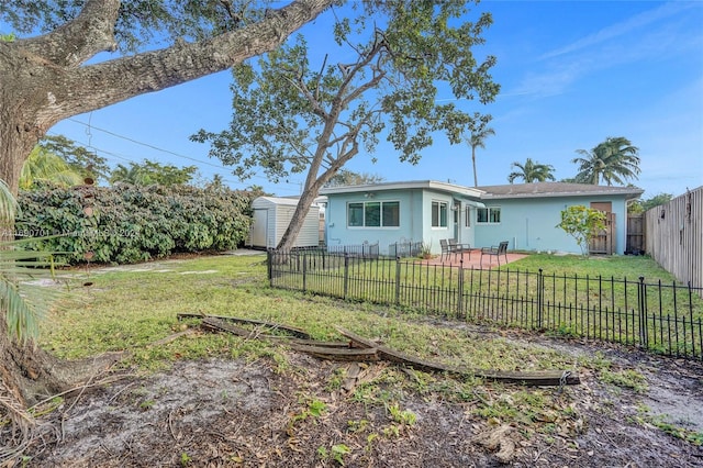 back of house with a storage unit and a yard