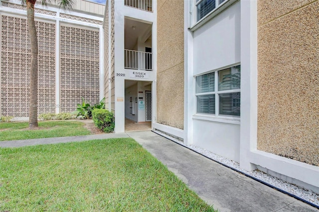 property entrance featuring a lawn and a balcony