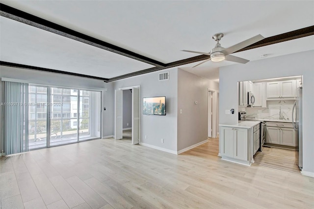 unfurnished living room with light hardwood / wood-style floors, beamed ceiling, and ceiling fan