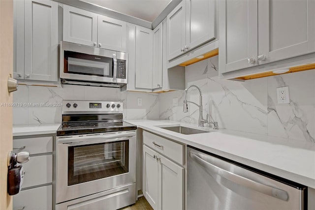 kitchen featuring tasteful backsplash, appliances with stainless steel finishes, sink, and light stone counters