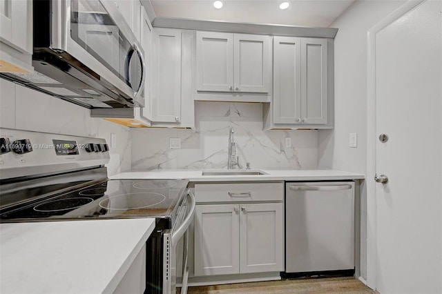 kitchen with stainless steel appliances, light hardwood / wood-style floors, sink, and tasteful backsplash