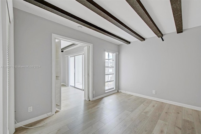 unfurnished room with beam ceiling and light wood-type flooring