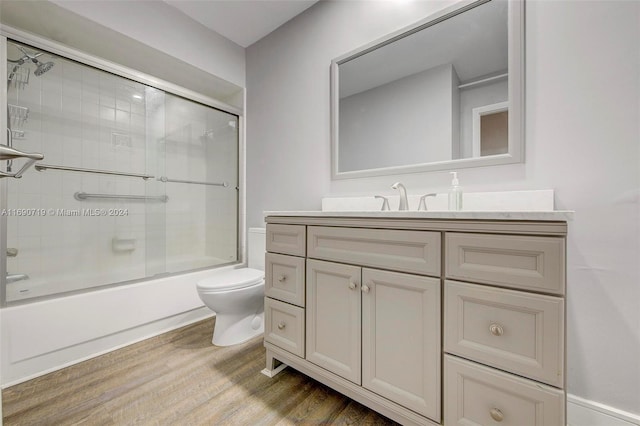 full bathroom with toilet, vanity, bath / shower combo with glass door, and wood-type flooring