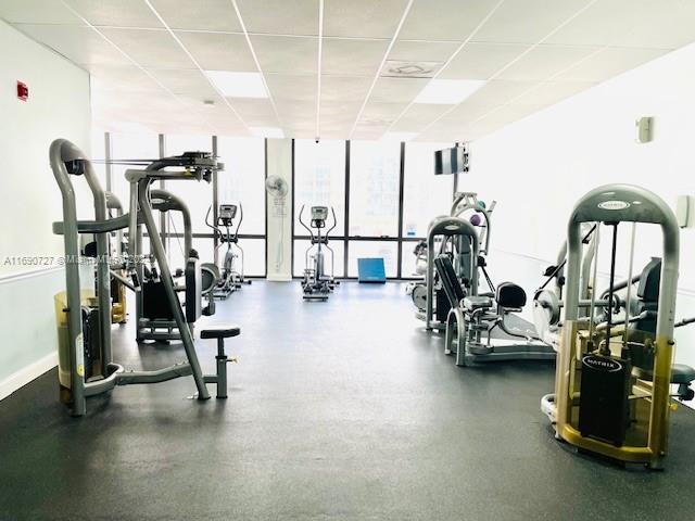 workout area with a drop ceiling and expansive windows