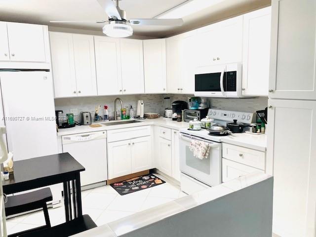 kitchen featuring white appliances, white cabinetry, and sink