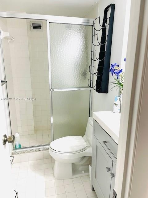 bathroom with tile patterned flooring, vanity, toilet, and a shower with door