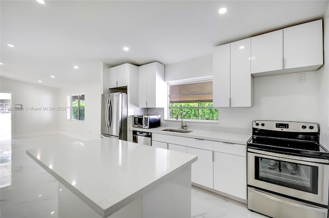 kitchen featuring white cabinetry, appliances with stainless steel finishes, sink, and a kitchen island