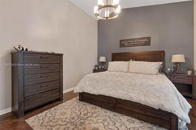 bedroom featuring dark hardwood / wood-style flooring, lofted ceiling, and an inviting chandelier