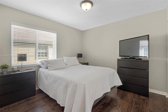 bedroom featuring a textured ceiling, multiple windows, and dark hardwood / wood-style floors