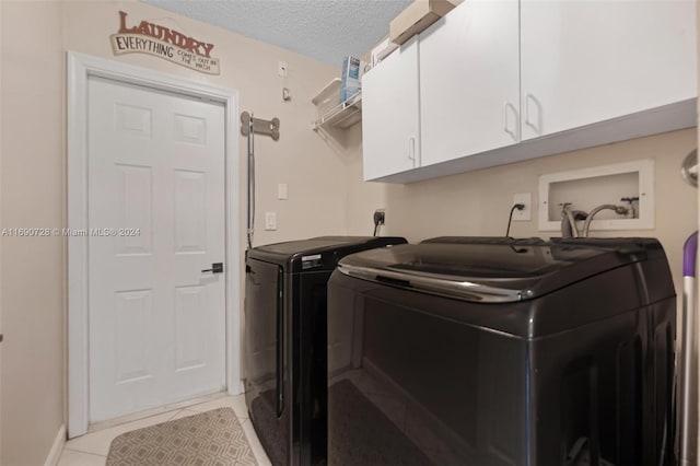 laundry room featuring cabinets, independent washer and dryer, light tile patterned floors, and a textured ceiling