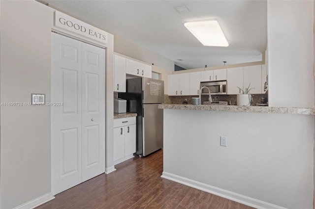 kitchen with stainless steel appliances, a textured ceiling, dark hardwood / wood-style flooring, white cabinets, and kitchen peninsula