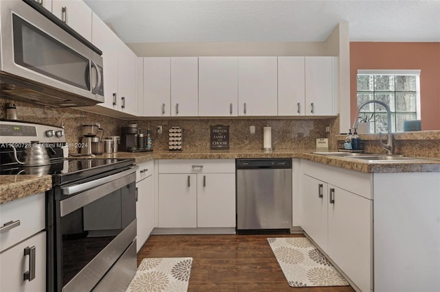 kitchen featuring white cabinetry, sink, appliances with stainless steel finishes, dark hardwood / wood-style floors, and decorative backsplash